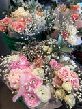 Bouquets of pink and white flowers with baby's breath on a table.